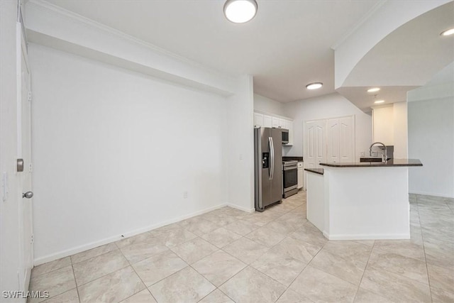 12980 Positano Cir Unit 306, Naples, FL 34105 - kitchen with stainless steel appliances, dark countertops, white cabinets, ornamental molding, and a peninsula