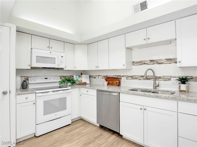 1492 La Petite Ct, Naples, FL 34104 - kitchen featuring white appliances, white cabinetry, decorative backsplash, light stone counters, and light wood-type flooring