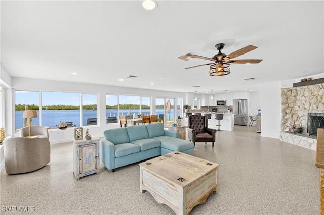 867 Oak St, Fort Myers Beach, FL 33931 - living area featuring a ceiling fan, a stone fireplace, recessed lighting, a water view, and dark speckled floor