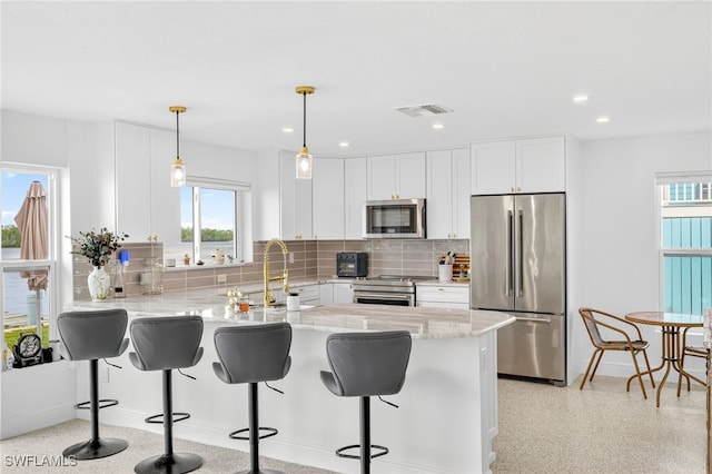 867 Oak St, Fort Myers Beach, FL 33931 - kitchen featuring appliances with stainless steel finishes, a peninsula, backsplash, white cabinetry, and light stone countertops