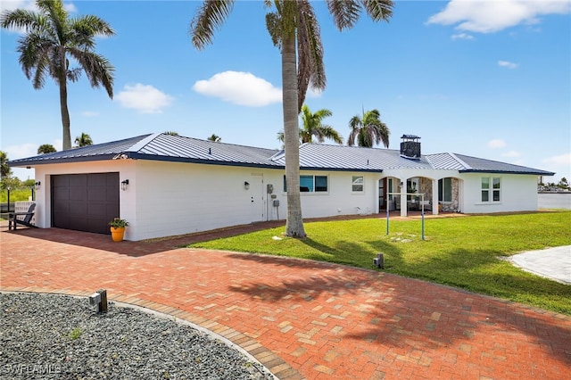 867 Oak St, Fort Myers Beach, FL 33931 - view of front facade with a standing seam roof, an attached garage, a metal roof, a front yard, and decorative driveway