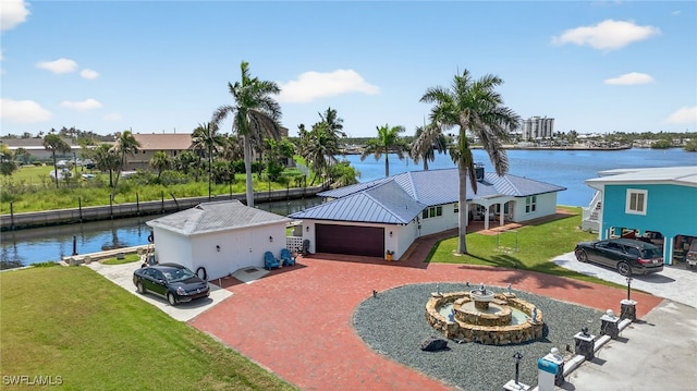 867 Oak St, Fort Myers Beach, FL 33931 - view of front of home featuring driveway, a front yard, a water view, stucco siding, and an attached garage