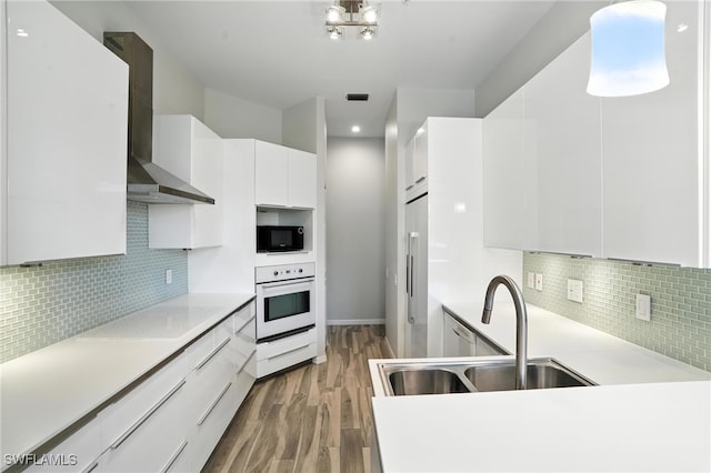 1000 L Ambiance Cir Unit 205, Naples, FL 34108 - kitchen featuring oven, wall chimney exhaust hood, light wood-type flooring, modern cabinets, and light countertops