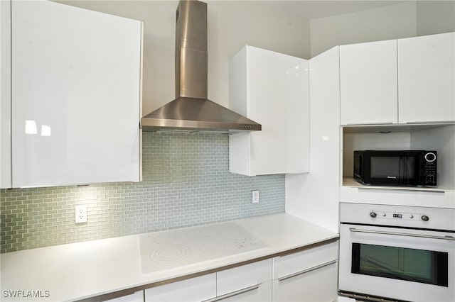1000 L Ambiance Cir Unit 205, Naples, FL 34108 - kitchen featuring wall chimney range hood, white appliances, white cabinetry, light countertops, and tasteful backsplash