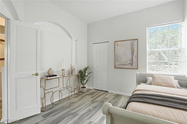 1000 L Ambiance Cir Unit 205, Naples, FL 34108 - bedroom featuring wood finished floors, arched walkways, and a closet
