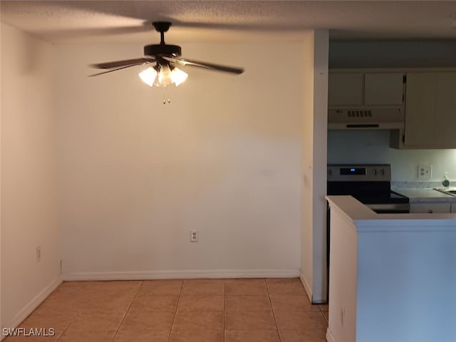 kitchen featuring under cabinet range hood, range with electric cooktop, light tile patterned floors, ceiling fan, and a textured ceiling