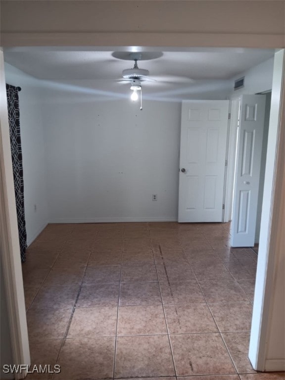 tiled empty room featuring a ceiling fan