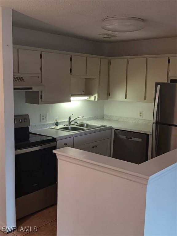 kitchen with appliances with stainless steel finishes, range hood, tile patterned floors, light countertops, and white cabinetry