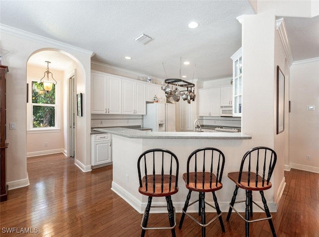 13915 Collier Blvd, Naples, FL 34119 - kitchen with white appliances, white cabinets, a kitchen bar, dark wood finished floors, and crown molding
