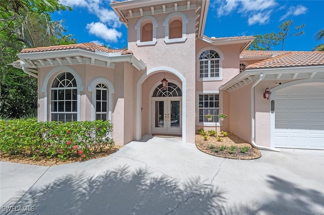 13915 Collier Blvd, Naples, FL 34119 - entrance to property with french doors, stucco siding, an attached garage, and a tiled roof