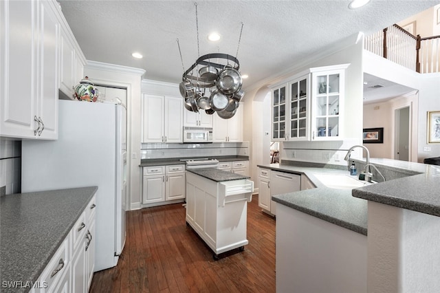 13915 Collier Blvd, Naples, FL 34119 - kitchen with white appliances, white cabinetry, ornamental molding, glass insert cabinets, and dark wood-type flooring