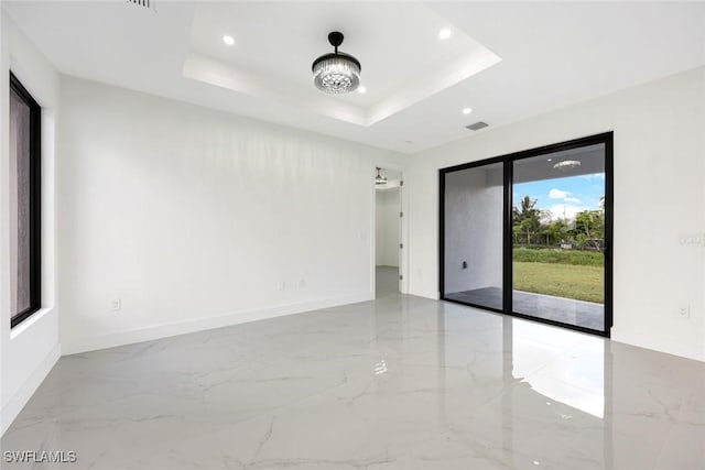 147 Partridge St, Lehigh Acres, FL 33974 - empty room featuring marble tiled floors, recessed lighting, and a tray ceiling