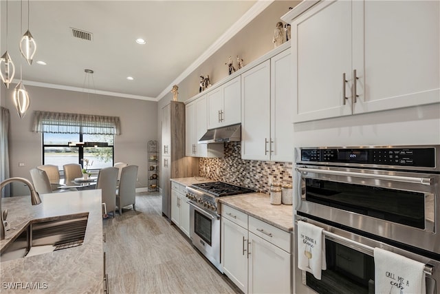 7478 Winding Cypress Dr, Naples, FL 34114 - kitchen featuring stainless steel appliances, crown molding, tasteful backsplash, white cabinets, and hanging light fixtures