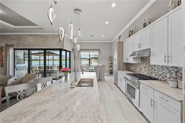 7478 Winding Cypress Dr, Naples, FL 34114 - kitchen with high end stainless steel range, under cabinet range hood, crown molding, white cabinetry, and decorative light fixtures