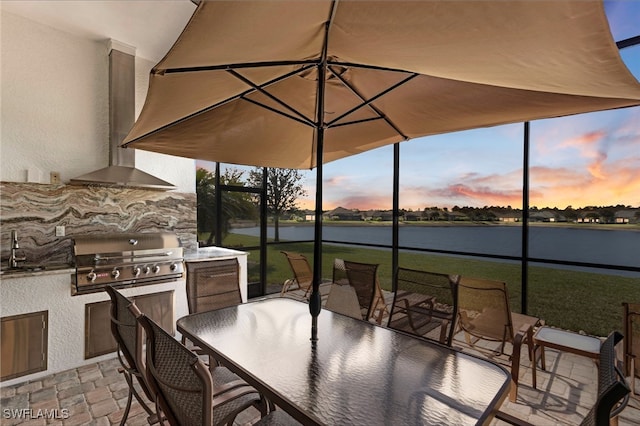 7478 Winding Cypress Dr, Naples, FL 34114 - patio terrace at dusk featuring an outdoor kitchen, a water view, a patio area, outdoor dining area, and a yard