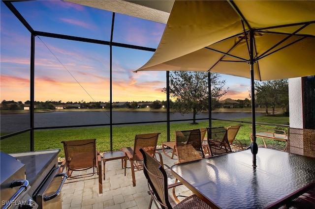 7478 Winding Cypress Dr, Naples, FL 34114 - patio terrace at dusk featuring a water view, a patio area, outdoor dining space, a lawn, and glass enclosure