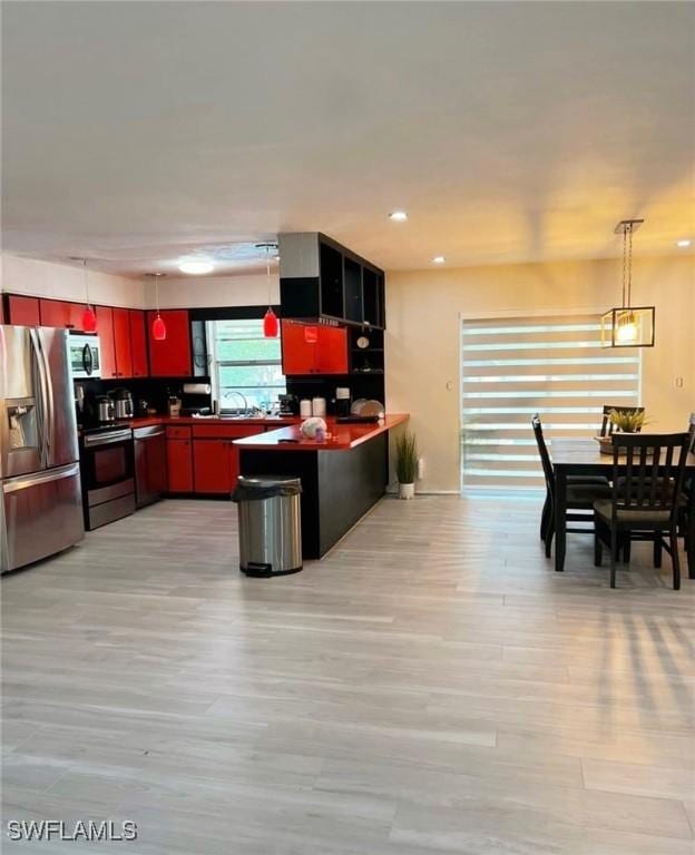 1407 Alwynne Dr, Lehigh Acres, FL 33936 - kitchen with appliances with stainless steel finishes, dark countertops, light wood-style floors, a peninsula, and recessed lighting