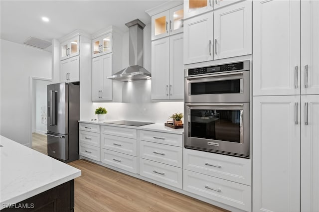 7637 Mulberry Ln, Naples, FL 34114 - kitchen featuring appliances with stainless steel finishes, wall chimney exhaust hood, white cabinetry, light wood-type flooring, and glass insert cabinets