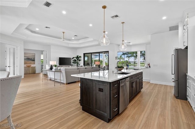 7637 Mulberry Ln, Naples, FL 34114 - kitchen featuring appliances with stainless steel finishes, light countertops, light wood-style floors, an island with sink, and white cabinetry