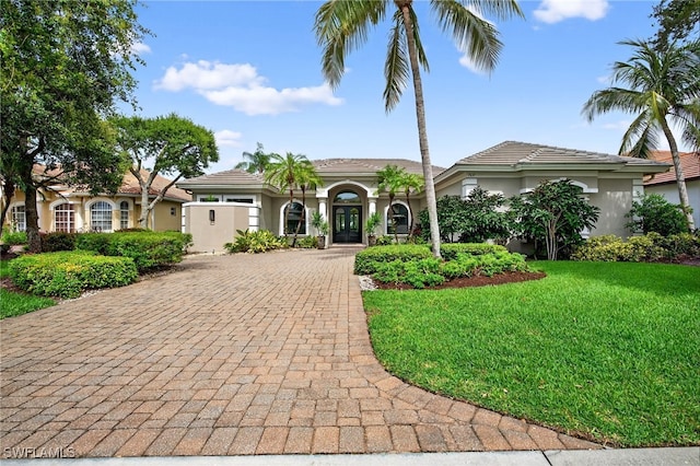 7637 Mulberry Ln, Naples, FL 34114 - mediterranean / spanish home with decorative driveway, stucco siding, a front lawn, and french doors