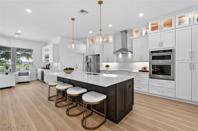 7637 Mulberry Ln, Naples, FL 34114 - kitchen with wall chimney exhaust hood, appliances with stainless steel finishes, light wood finished floors, recessed lighting, and light countertops