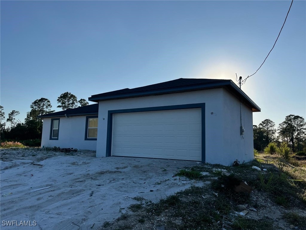 716 Joponica Ave S, Lehigh Acres, FL 33974 - view of home's exterior featuring stucco siding and an attached garage