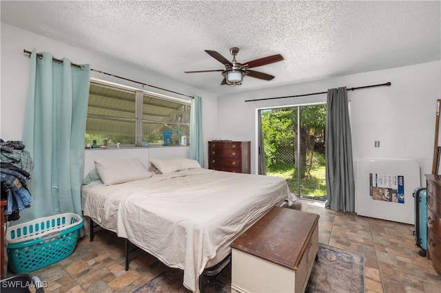 17041 Tarpon Way N, Fort Myers, FL 33917 - bedroom featuring access to exterior, a textured ceiling, ceiling fan, and stone finish flooring