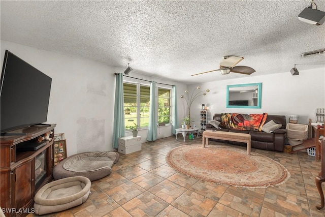 17041 Tarpon Way N, Fort Myers, FL 33917 - living room with ceiling fan, a textured ceiling, stone finish floors, and a wood stove