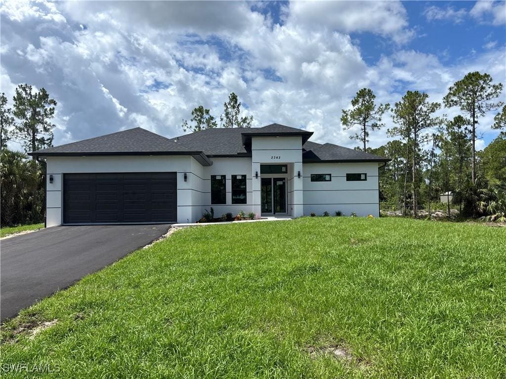 2342 10th Ave SE, Naples, FL 34117 - prairie-style home with asphalt driveway, an attached garage, a front lawn, and stucco siding