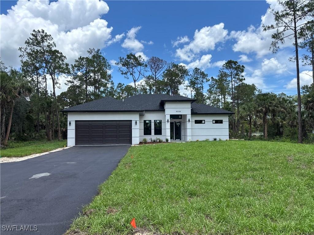 4259 12th Ave SE, Naples, FL 34117 - view of front of house featuring asphalt driveway, a garage, stucco siding, and a front lawn