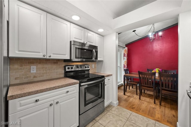 770 Wilson Ave, Fort Myers, FL 33919 - kitchen with appliances with stainless steel finishes, recessed lighting, light tile patterned floors, white cabinetry, and tasteful backsplash
