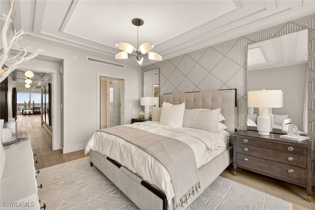 13925 Old Coast Rd Unit 403, Naples, FL 34110 - bedroom with light wood-type flooring, a chandelier, an accent wall, wallpapered walls, and a tray ceiling