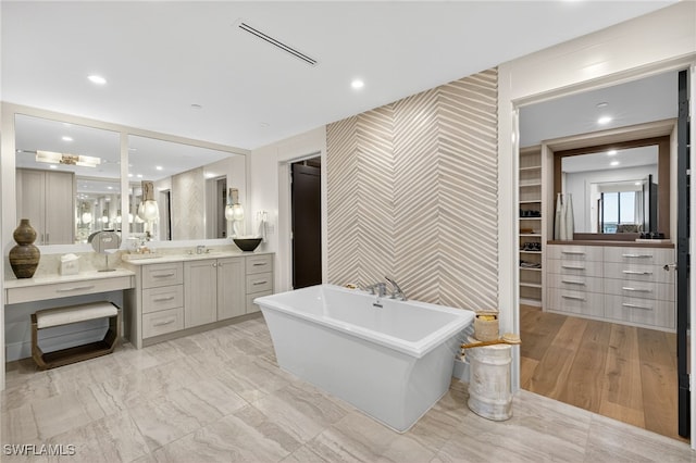 13925 Old Coast Rd Unit 403, Naples, FL 34110 - bathroom with an accent wall, wallpapered walls, vanity, a freestanding tub, and a spacious closet