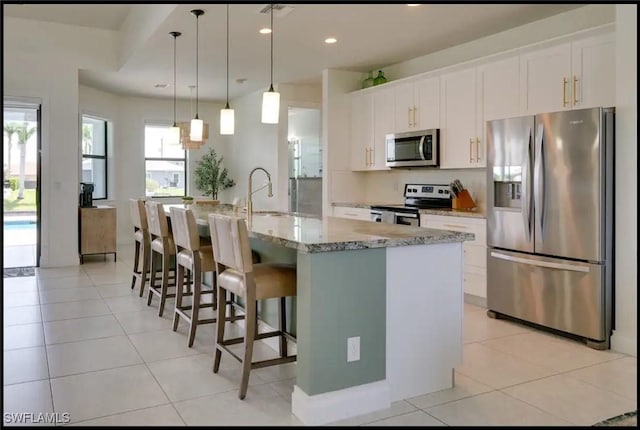 2229 SW 17th Pl, Cape Coral, FL 33991 - kitchen featuring stainless steel appliances, white cabinetry, a center island with sink, a kitchen breakfast bar, and decorative light fixtures