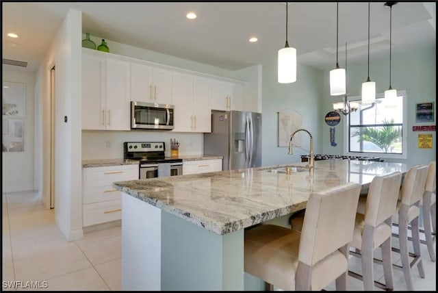 2229 SW 17th Pl, Cape Coral, FL 33991 - kitchen with appliances with stainless steel finishes, a large island, white cabinetry, light stone counters, and a breakfast bar area