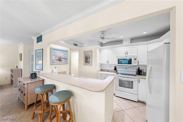 519 Seaview Ct Unit N4, Marco Island, FL 34145 - kitchen featuring white appliances, light tile patterned floors, white cabinetry, a kitchen bar, and light countertops
