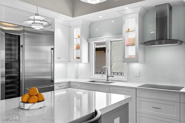 5850 Pelican Bay Blvd Unit C, Naples, FL 34108 - kitchen with wall chimney range hood, high end fridge, black electric cooktop, white cabinets, and glass insert cabinets
