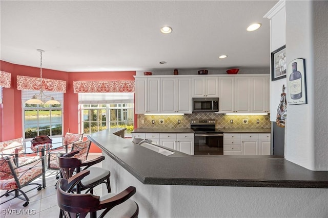 4660 Winged Foot Ct Unit 104, Naples, FL 34112 - kitchen with stainless steel microwave, electric range, dark countertops, white cabinets, and recessed lighting