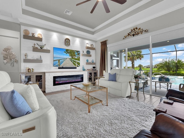 15904 Talon Ter, Punta Gorda, FL 33982 - living room featuring a raised ceiling, ceiling fan, a premium fireplace, ornamental molding, and wood finished floors