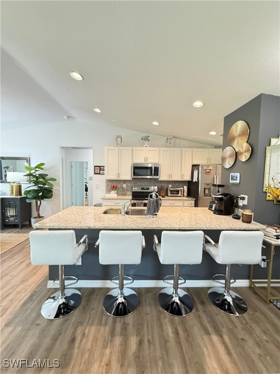 3006 Base Ct, Labelle, FL 33935 - kitchen with stainless steel appliances, lofted ceiling, light wood-style flooring, a kitchen bar, and white cabinetry