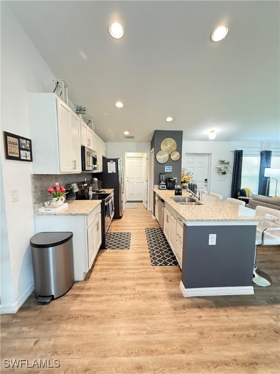 3006 Base Ct, Labelle, FL 33935 - kitchen with stainless steel appliances, white cabinetry, light wood-style floors, recessed lighting, and light stone countertops