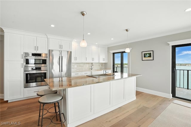 1100 S Collier Blvd Unit 723, Marco Island, FL 34145 - kitchen featuring stainless steel appliances, light wood-style floors, white cabinets, tasteful backsplash, and ornamental molding