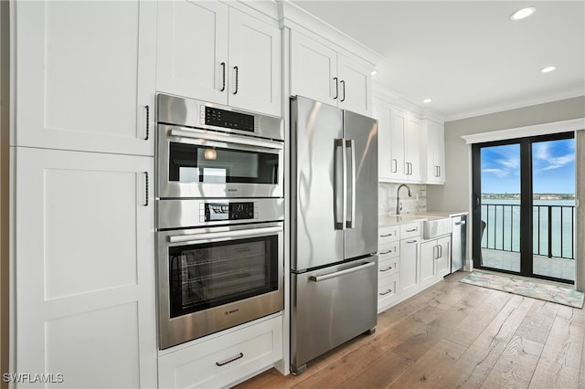 1100 S Collier Blvd Unit 723, Marco Island, FL 34145 - kitchen with appliances with stainless steel finishes, ornamental molding, light wood-style flooring, white cabinetry, and recessed lighting