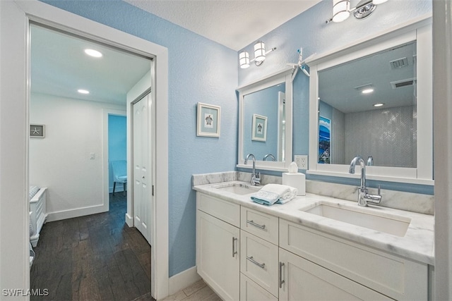 1129 8th Ter N, Naples, FL 34102 - full bath with double vanity, a textured wall, ensuite bathroom, wood finished floors, and recessed lighting