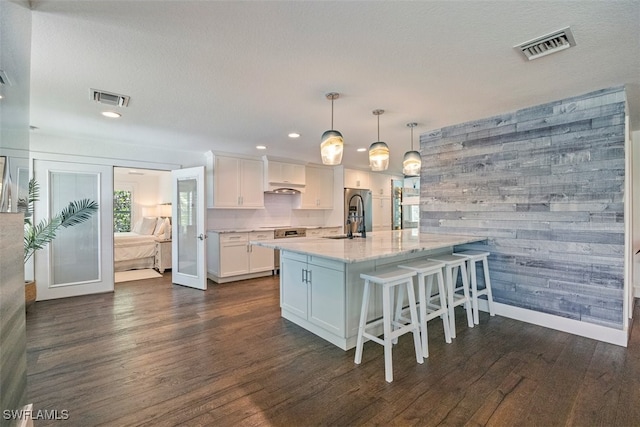 1129 8th Ter N, Naples, FL 34102 - kitchen with dark wood-type flooring, white cabinetry, recessed lighting, light stone counters, and wood walls