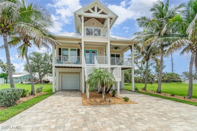 830 San Carlos Dr, Fort Myers Beach, FL 33931 - coastal inspired home with an attached garage, a front lawn, a porch, and decorative driveway