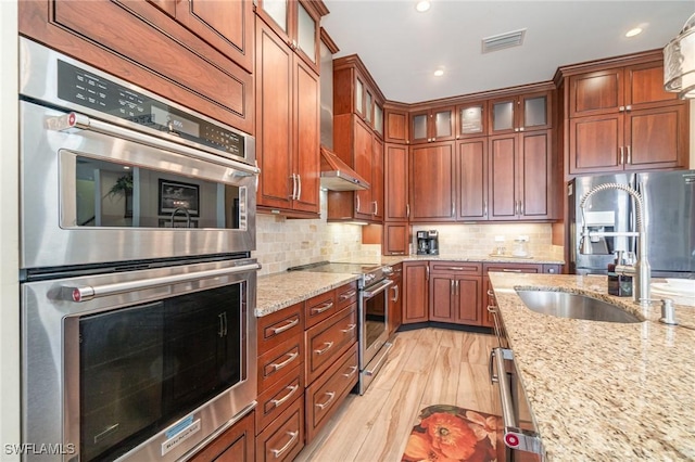 830 San Carlos Dr, Fort Myers Beach, FL 33931 - kitchen featuring appliances with stainless steel finishes, light stone countertops, decorative backsplash, brown cabinets, and recessed lighting