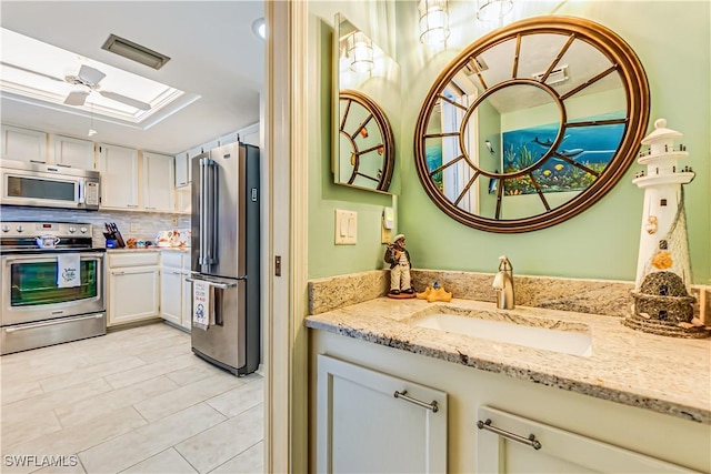 4531 Bay Beach Ln Unit 337, Fort Myers Beach, FL 33931 - kitchen featuring stainless steel appliances, a skylight, light stone countertops, decorative backsplash, and white cabinetry