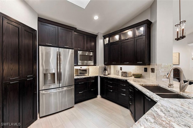 2322 River Reach Dr, Naples, FL 34104 - kitchen with stainless steel appliances, decorative backsplash, light stone counters, light wood-style floors, and vaulted ceiling