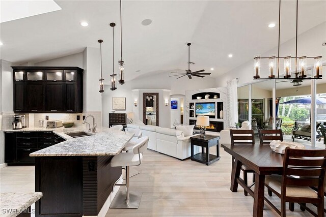 2322 River Reach Dr, Naples, FL 34104 - kitchen featuring vaulted ceiling, ceiling fan, dark cabinets, decorative backsplash, and open floor plan